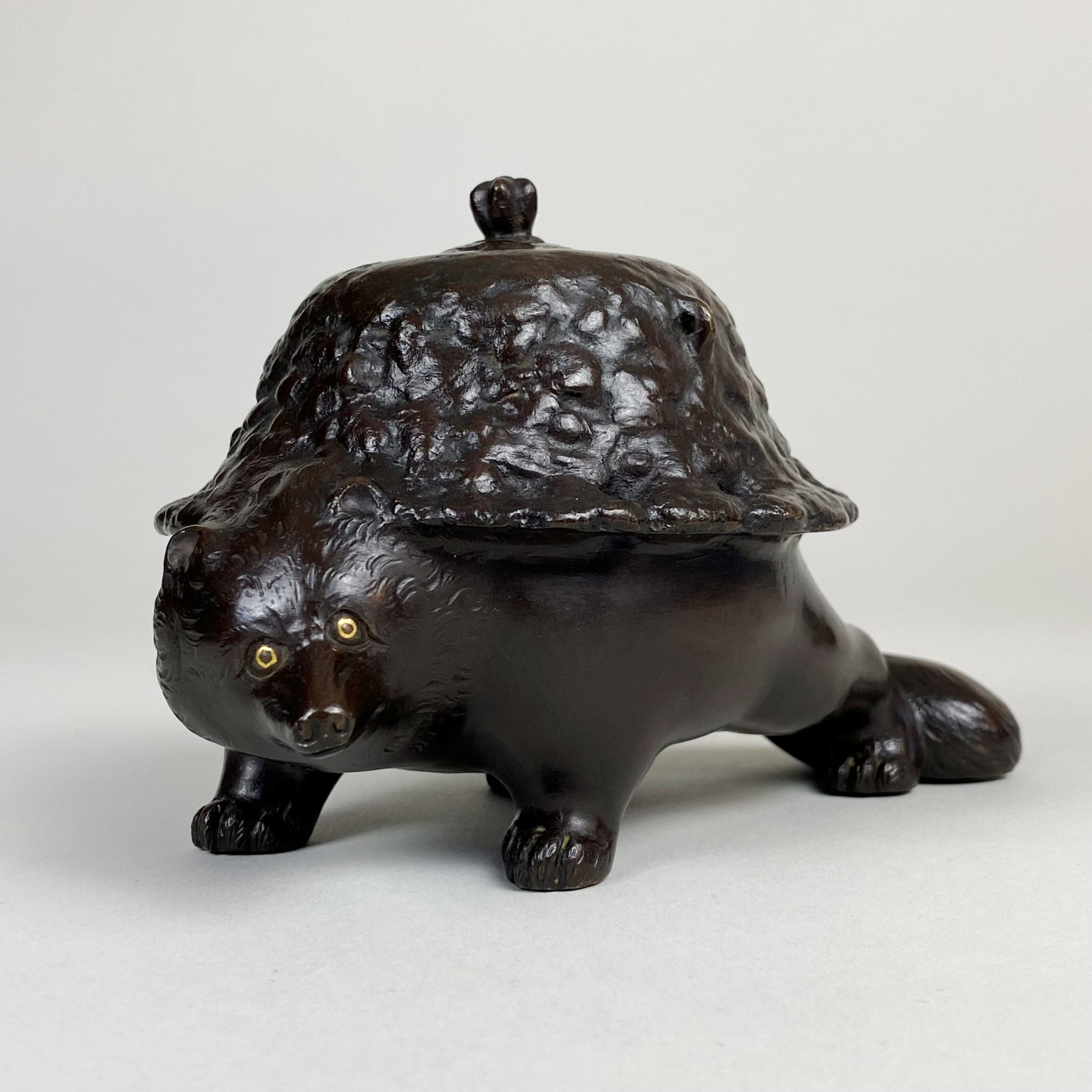A charming Bronze Okimono depicting a Tanuki transformed as a